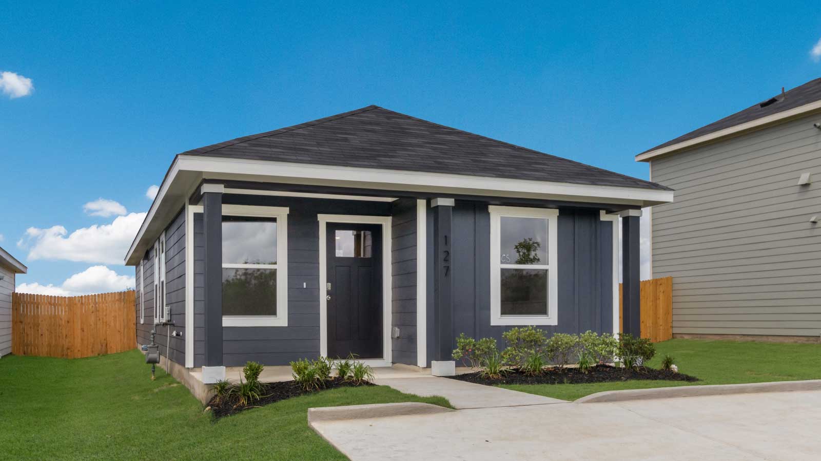 One story home with dark blue siding and large windows.