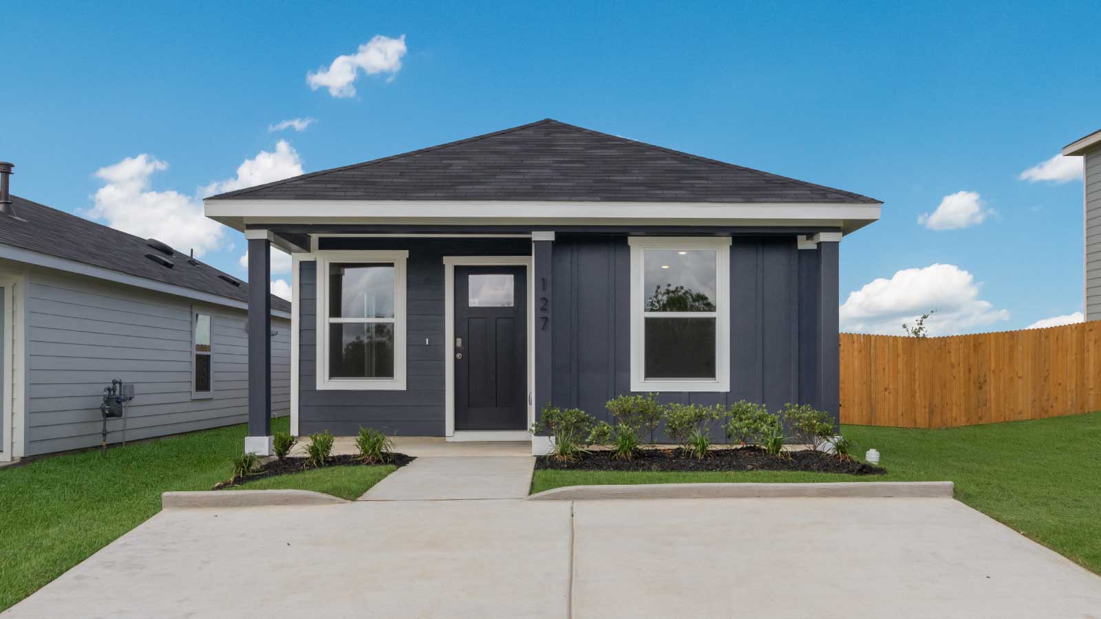 One story home with dark blue siding and large windows.