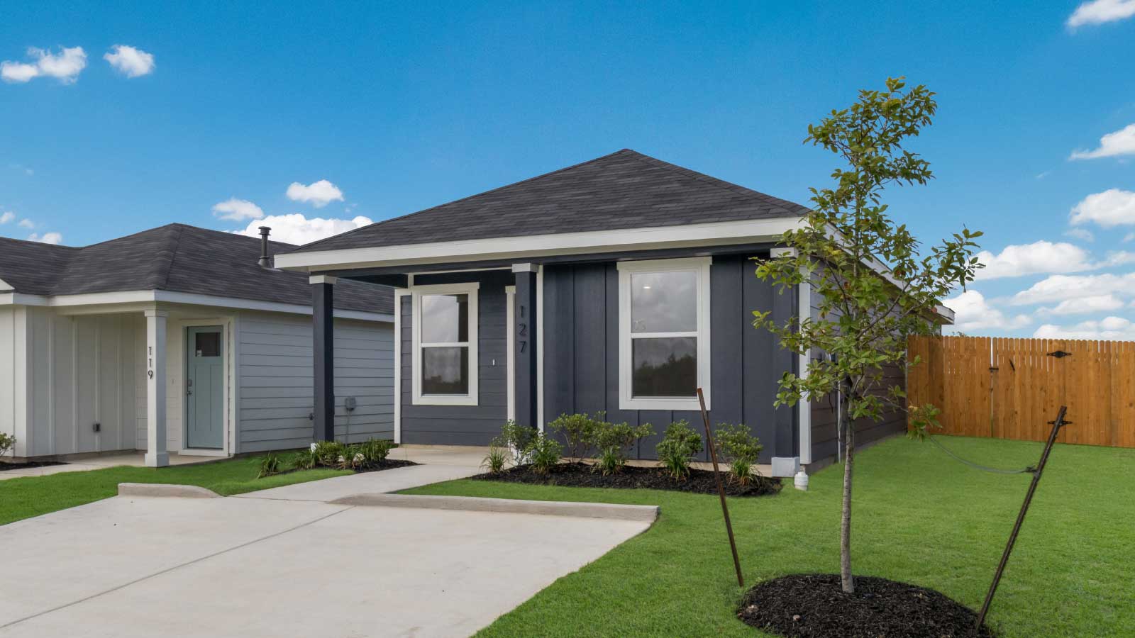 One story home with dark blue siding and large windows.