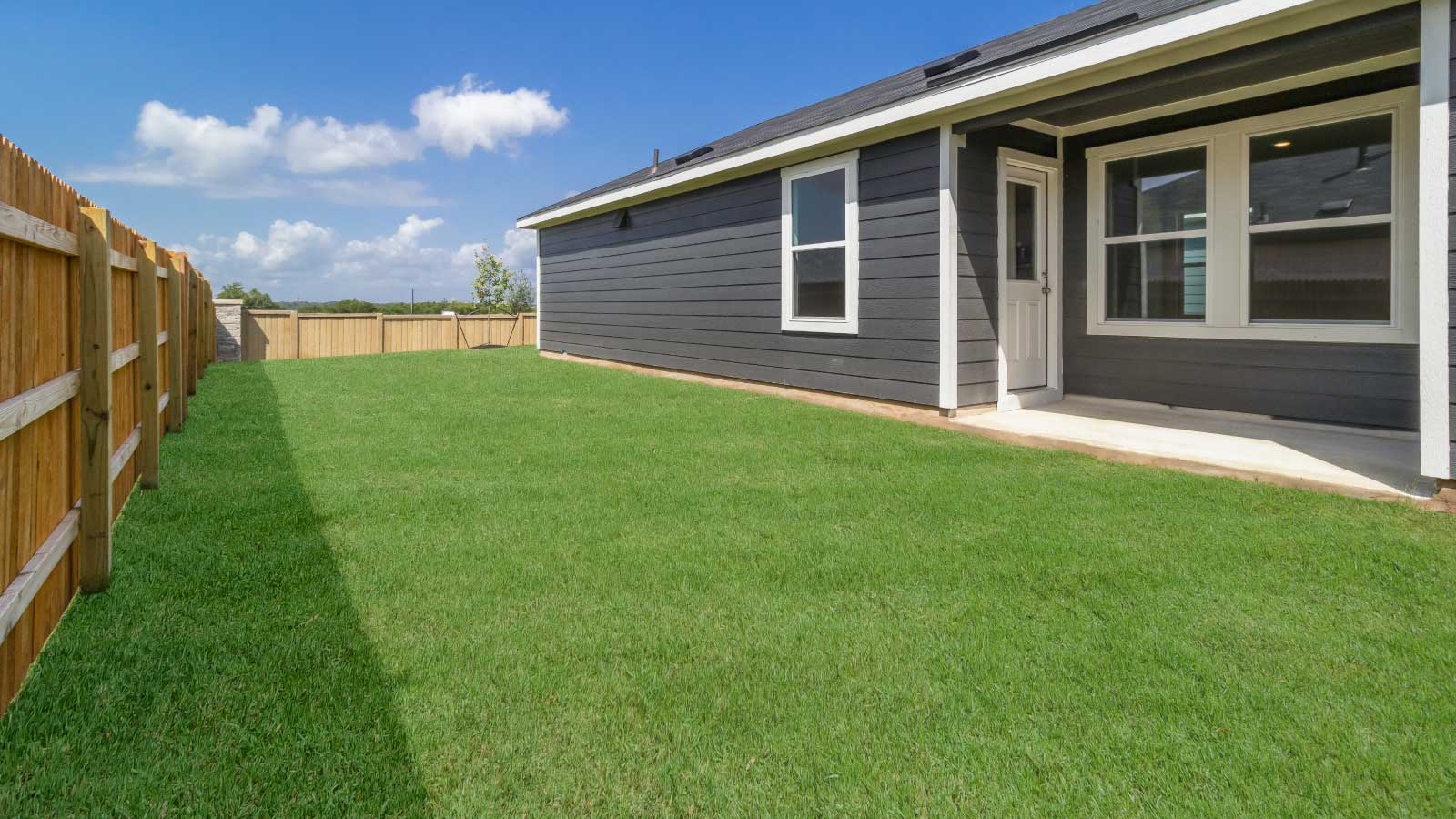 Backyard with a wooden fence and green grass.