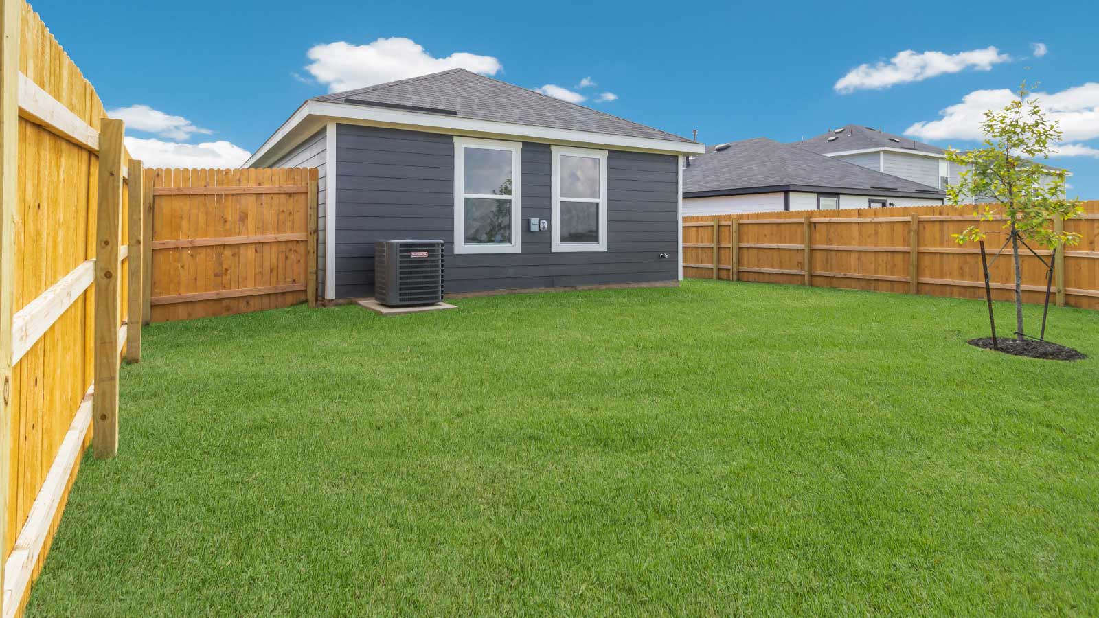 Backyard with a wooden fence and green grass.