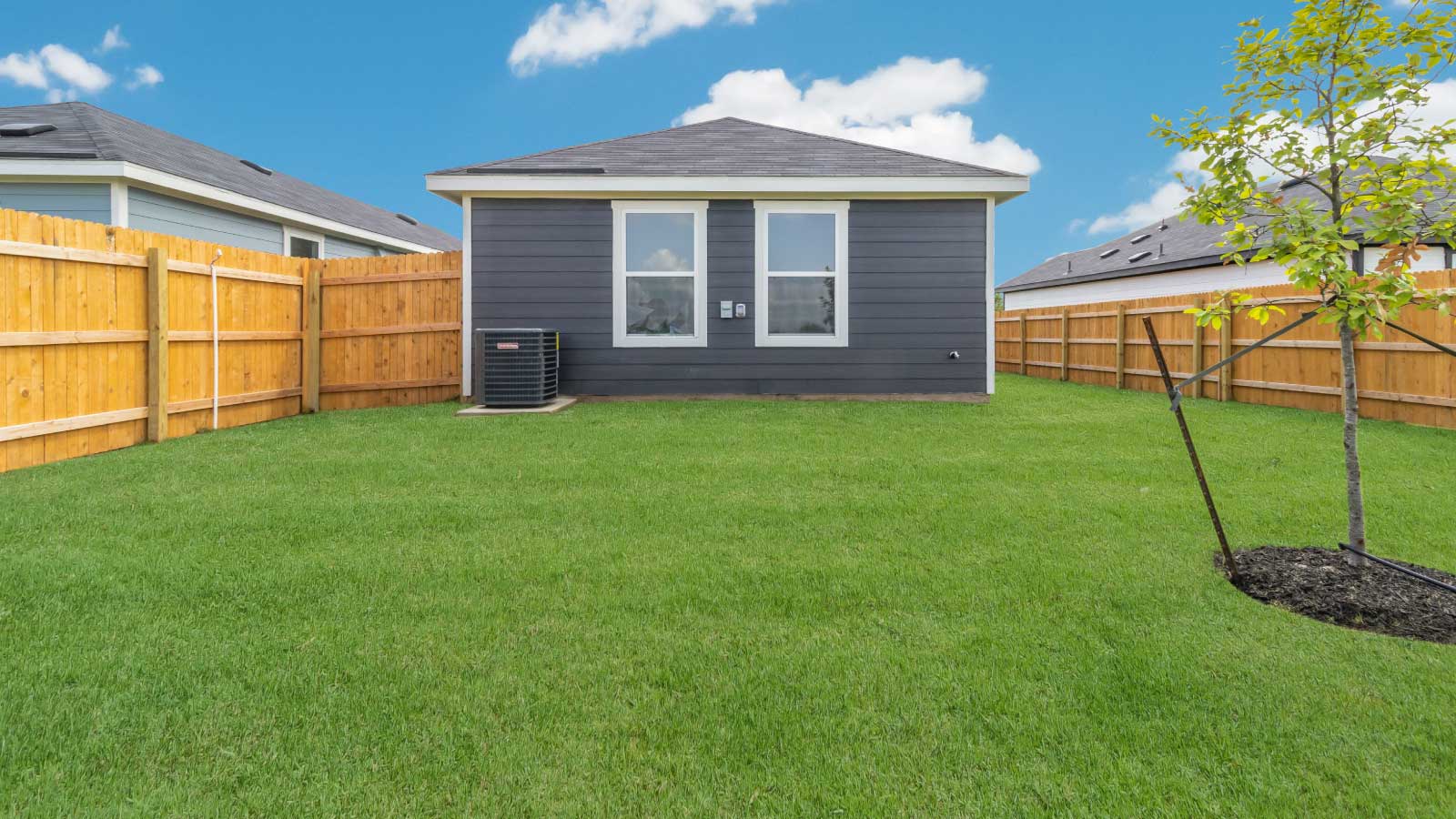 Backyard with a wooden fence and green grass.