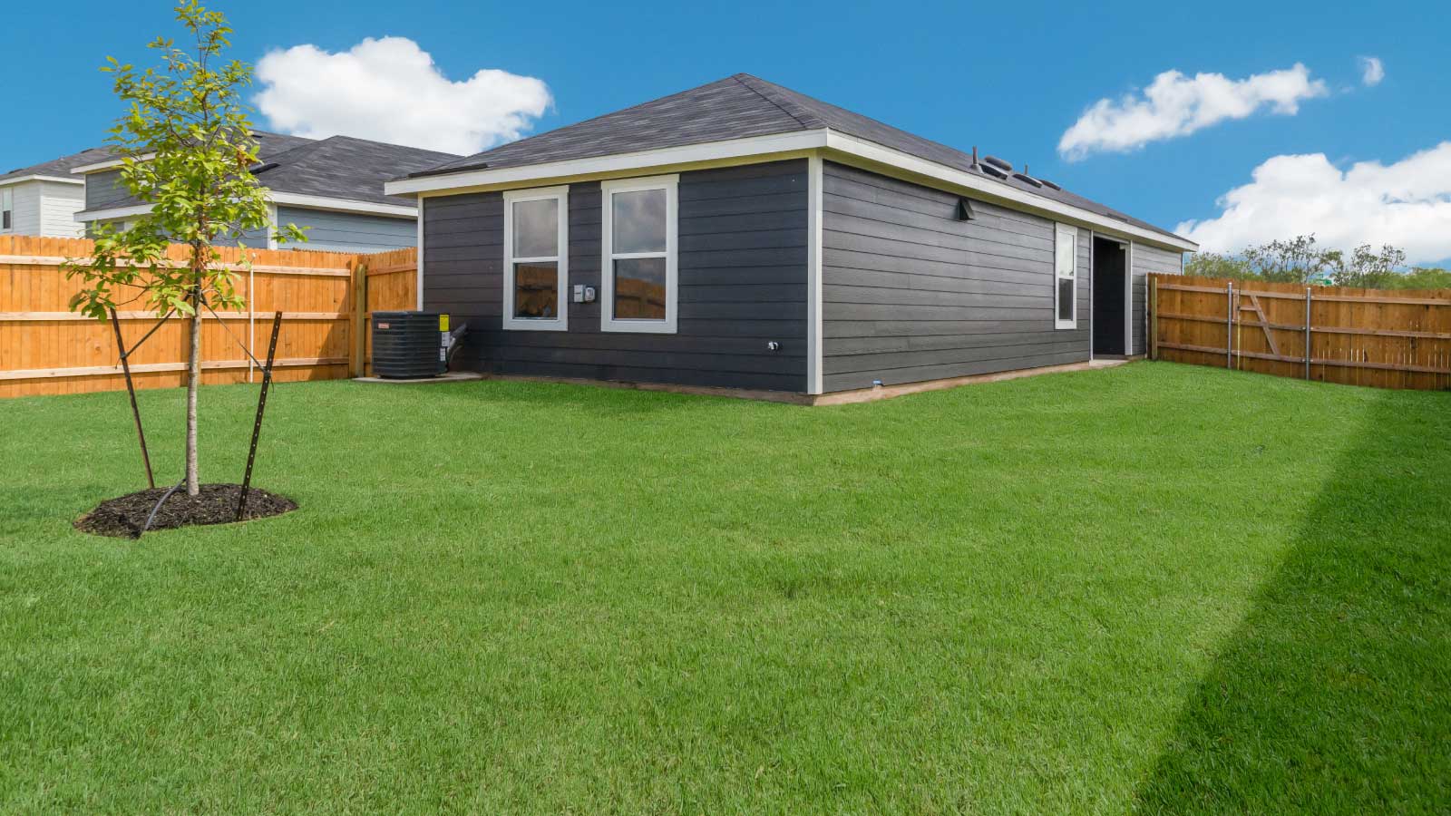 Backyard with a wooden fence and green grass.
