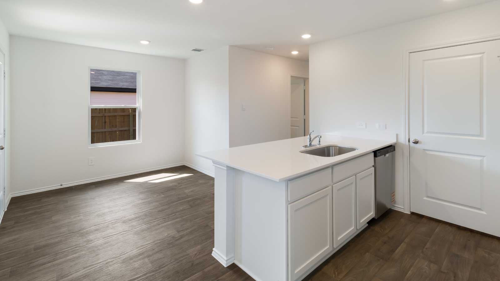 Kitchen with white cabinets, stainless steel appliances, and a large island connecting to dining area.