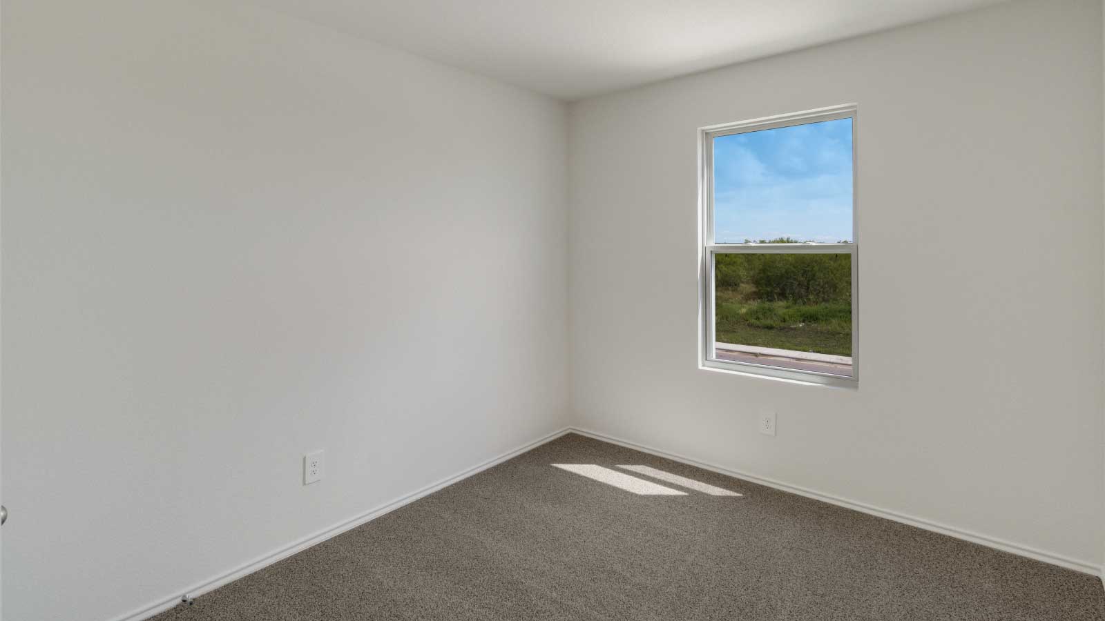 Bedroom with brown carpet, white walls, and a window.