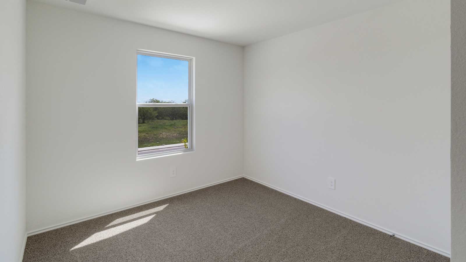 Bedroom with brown carpet, white walls, and a window.