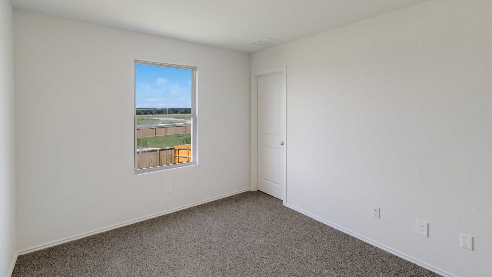 Bedroom with brown carpet, white walls, and a window.