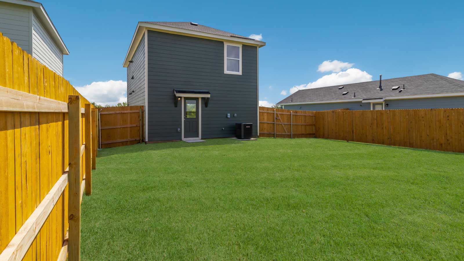 Backyard with a wooden fence and green grass.