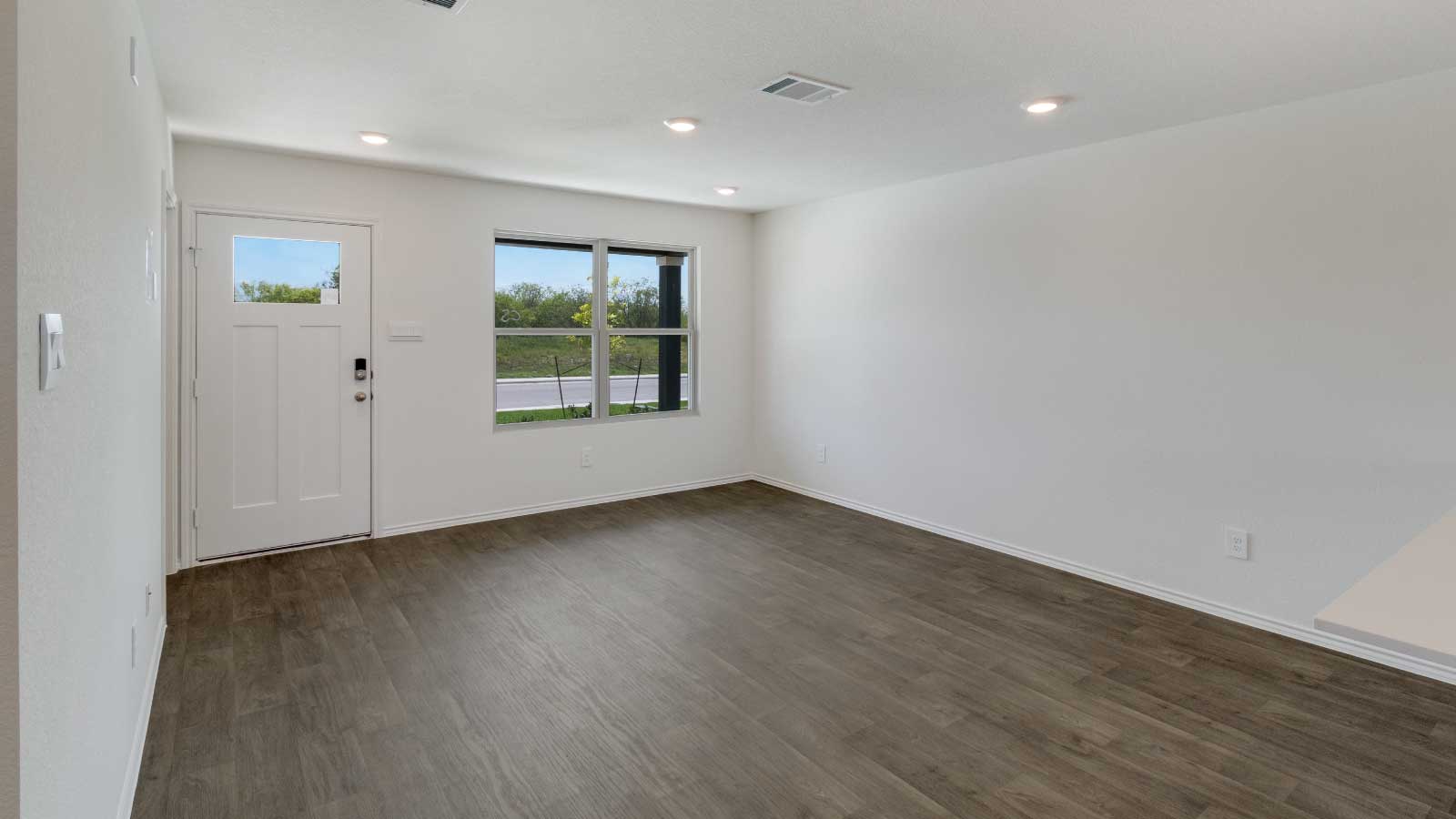 Entry and living room area with brown flooring and white walls.