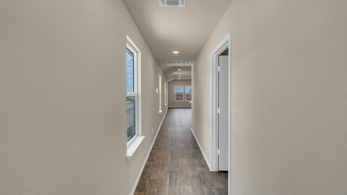 front entry way hallway of the home featuring light beige walls and rich brown floors