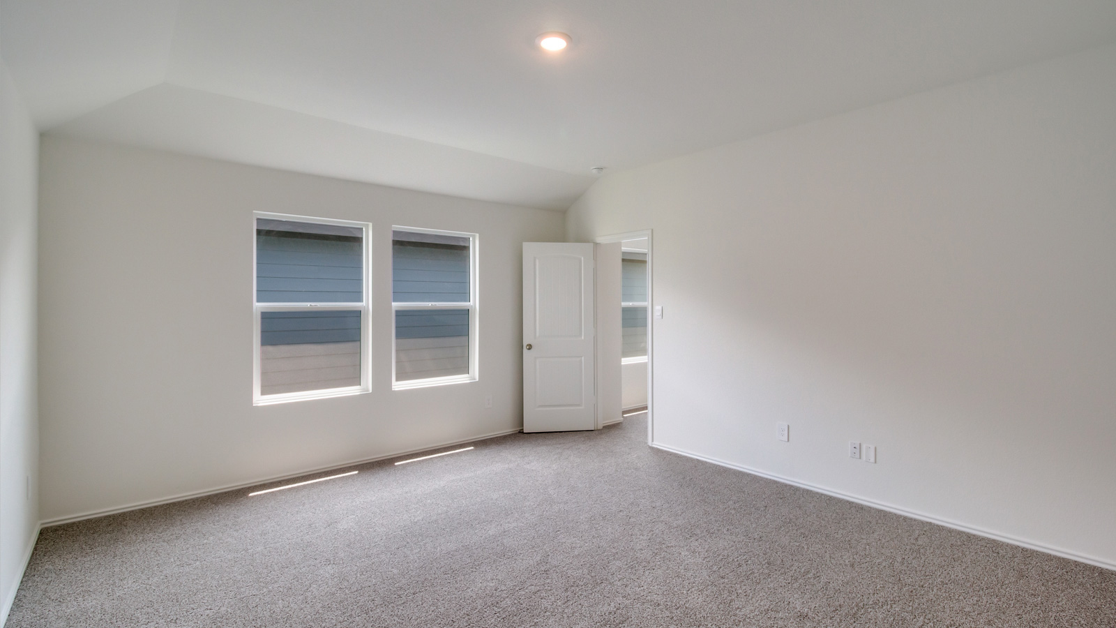 bedroom with beige carpet, white walls and 2 windows