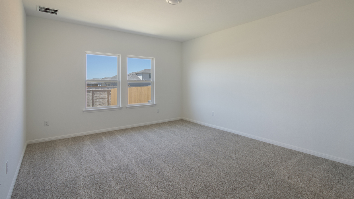 Bedroom with brown carpet, white walls, and large windows.