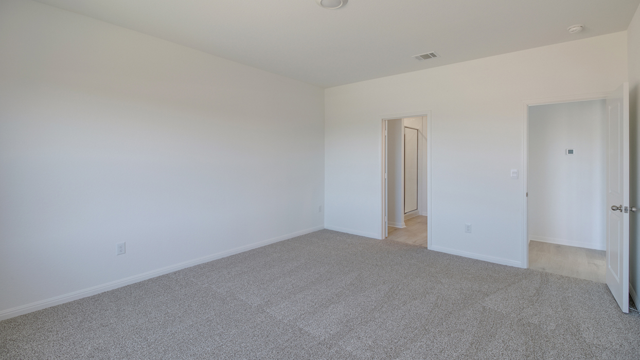 Bedroom with brown carpet, white walls, and a bathroom attached.