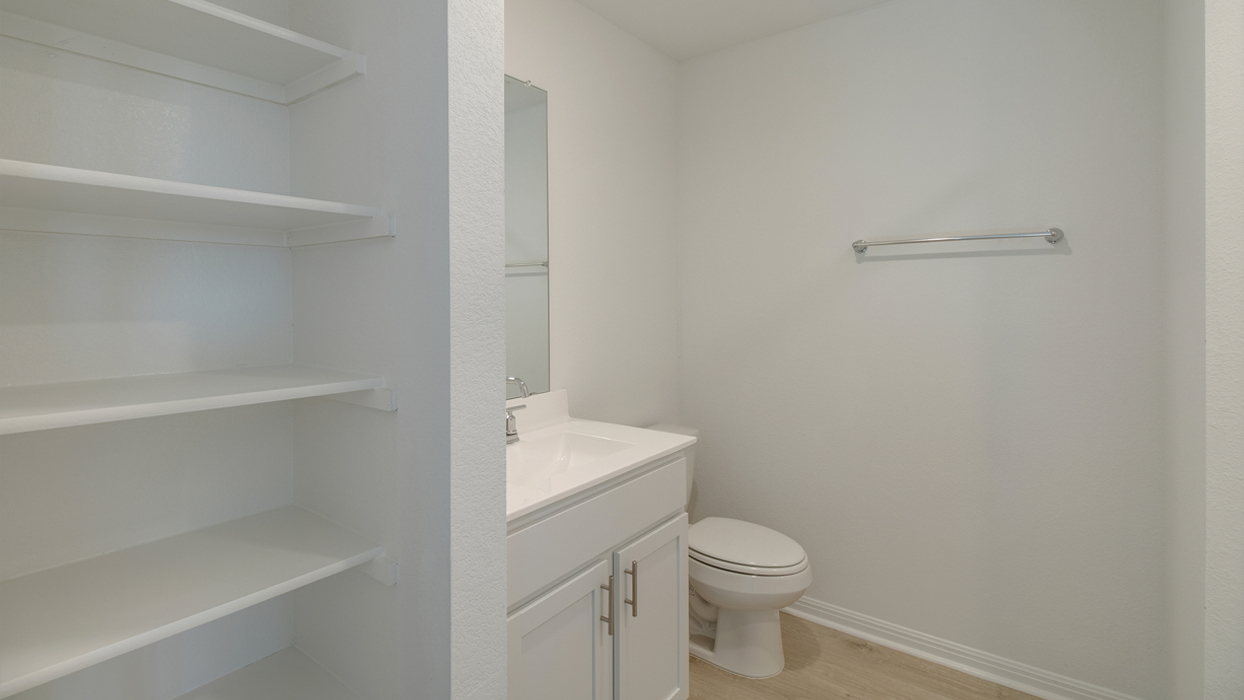Bathroom with built in shelving, a sink, and toilet.