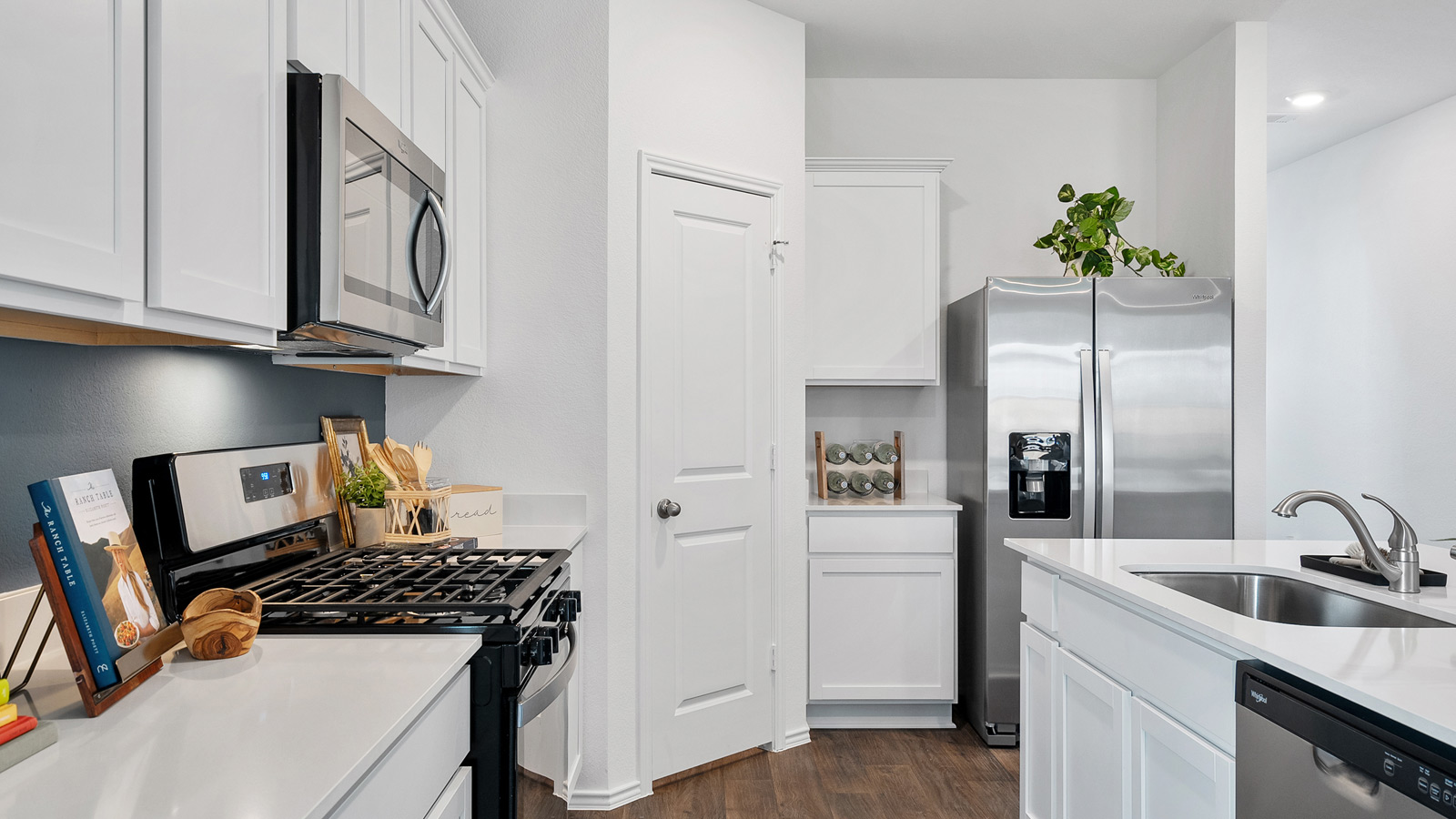 Side view of a kitchen with quartz countertops, white cabinetry, and a walk-in pantry