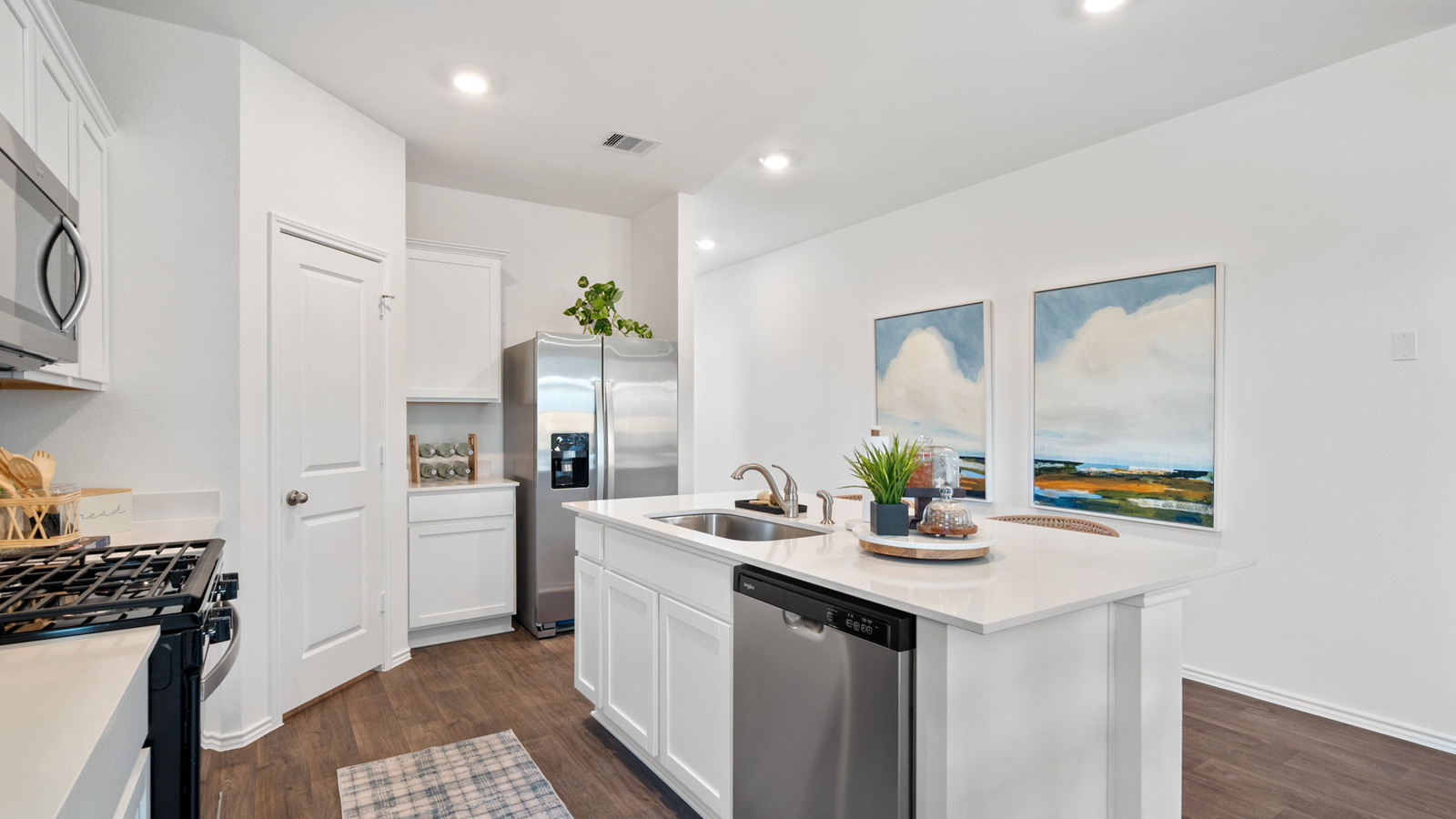 Kitchen with an island, a walk-in pantry, overhead lighting, and paintings on the wall