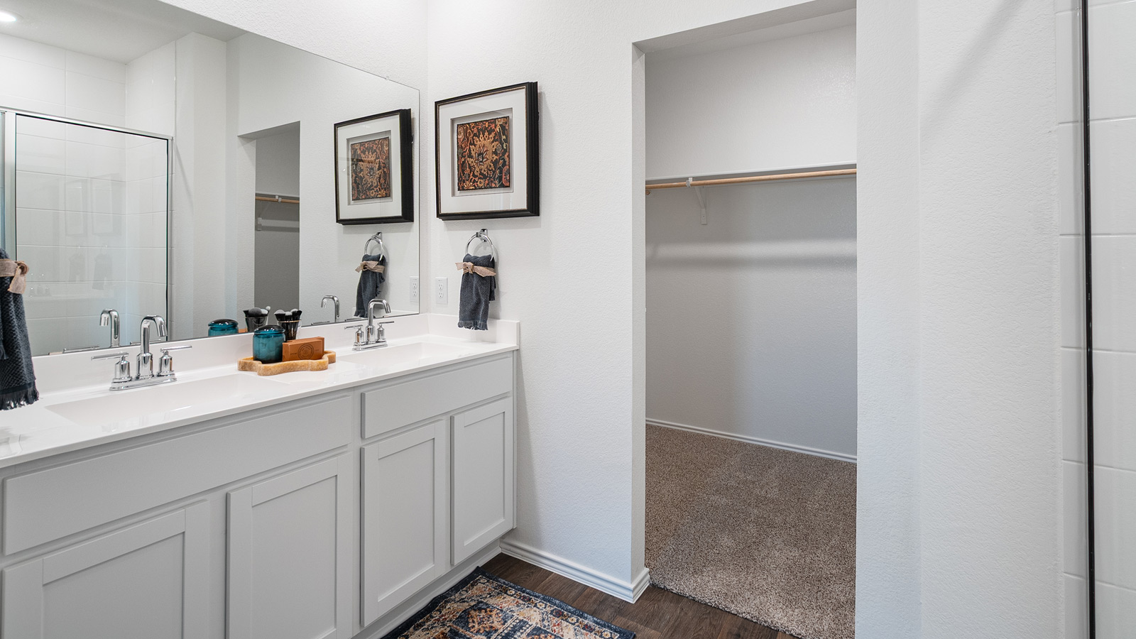 Bathroom with dual sinks, a large mirror, and a walk-in closet