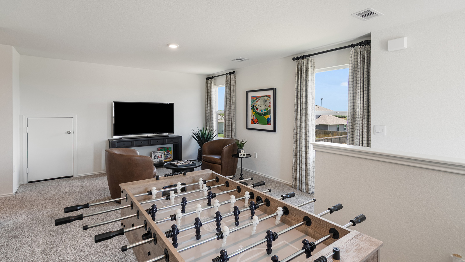 Game room with two windows and furnished with a foosball table, a seating area, a TV, and TV stand