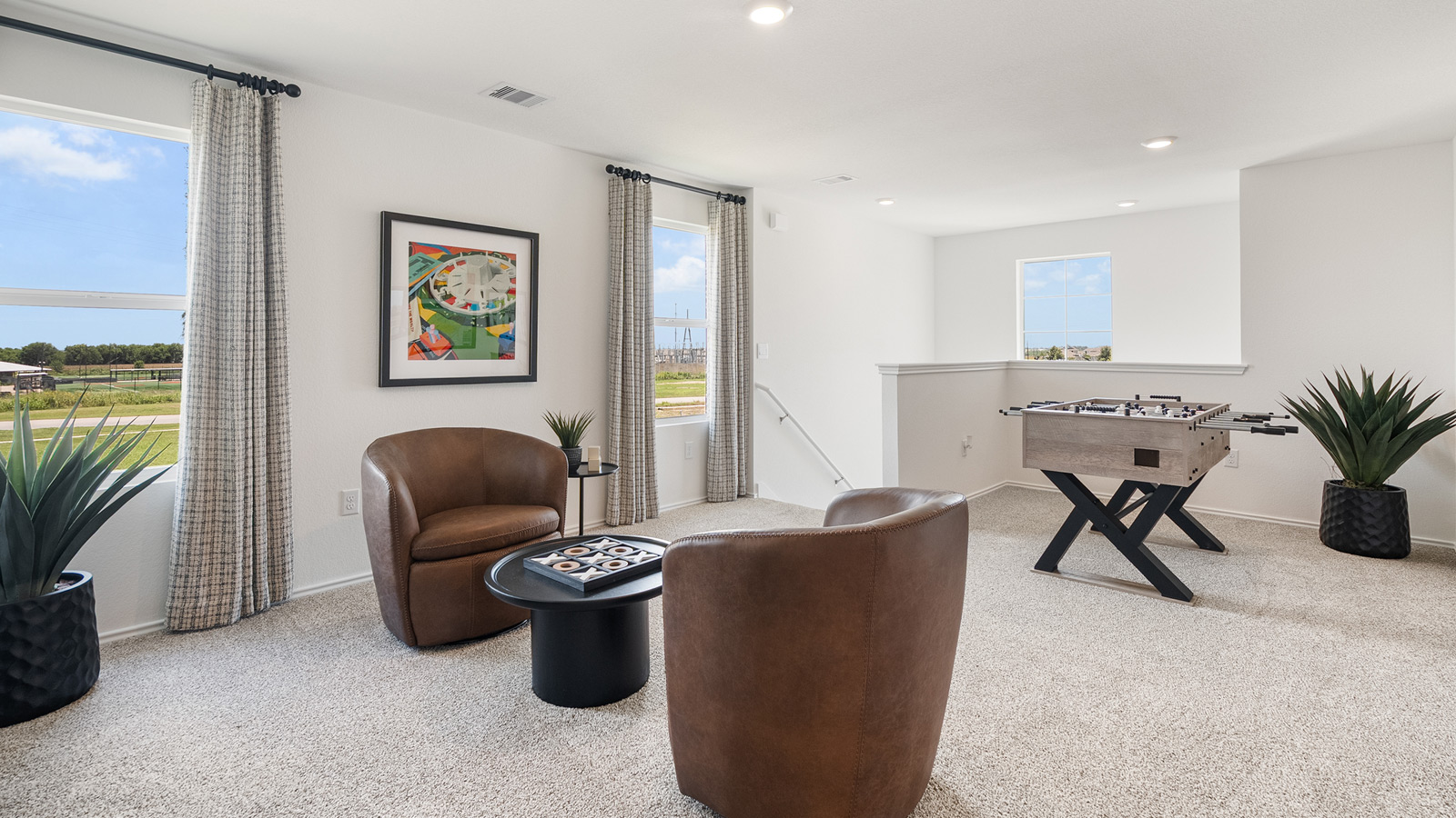 Game room with two windows and furnished with two chairs, a small round table, and a foosball table