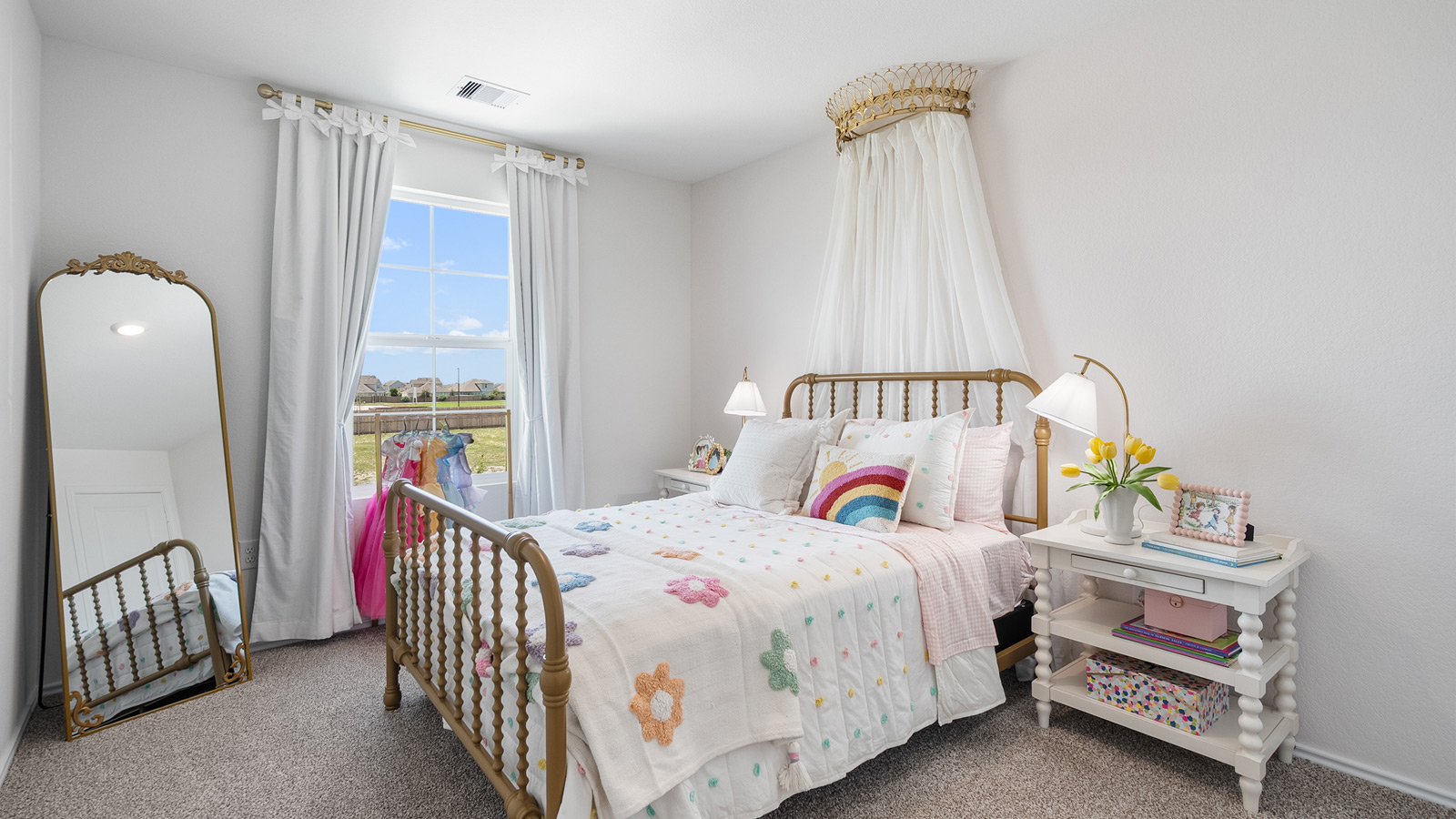 Bright bedroom with a small window and furnished with a floral bed, a mirror, and two white nightstands