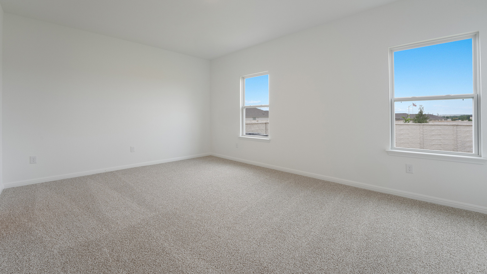 Main bedroom with carpeted floors and two windows.