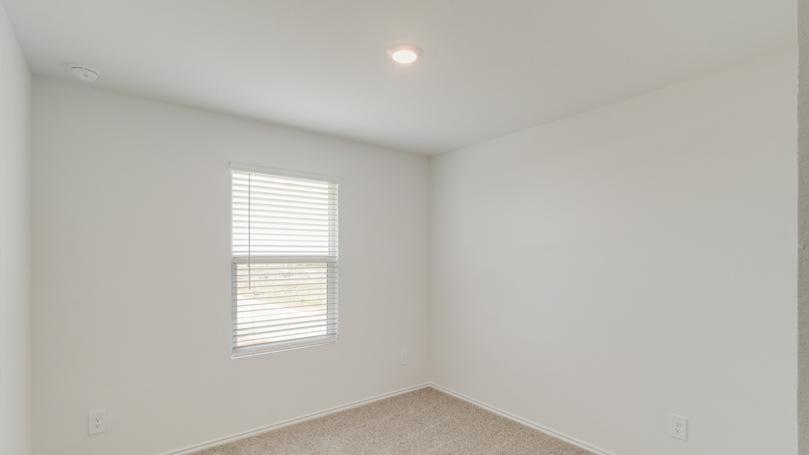 Bedroom with light brown carpet and white walls.