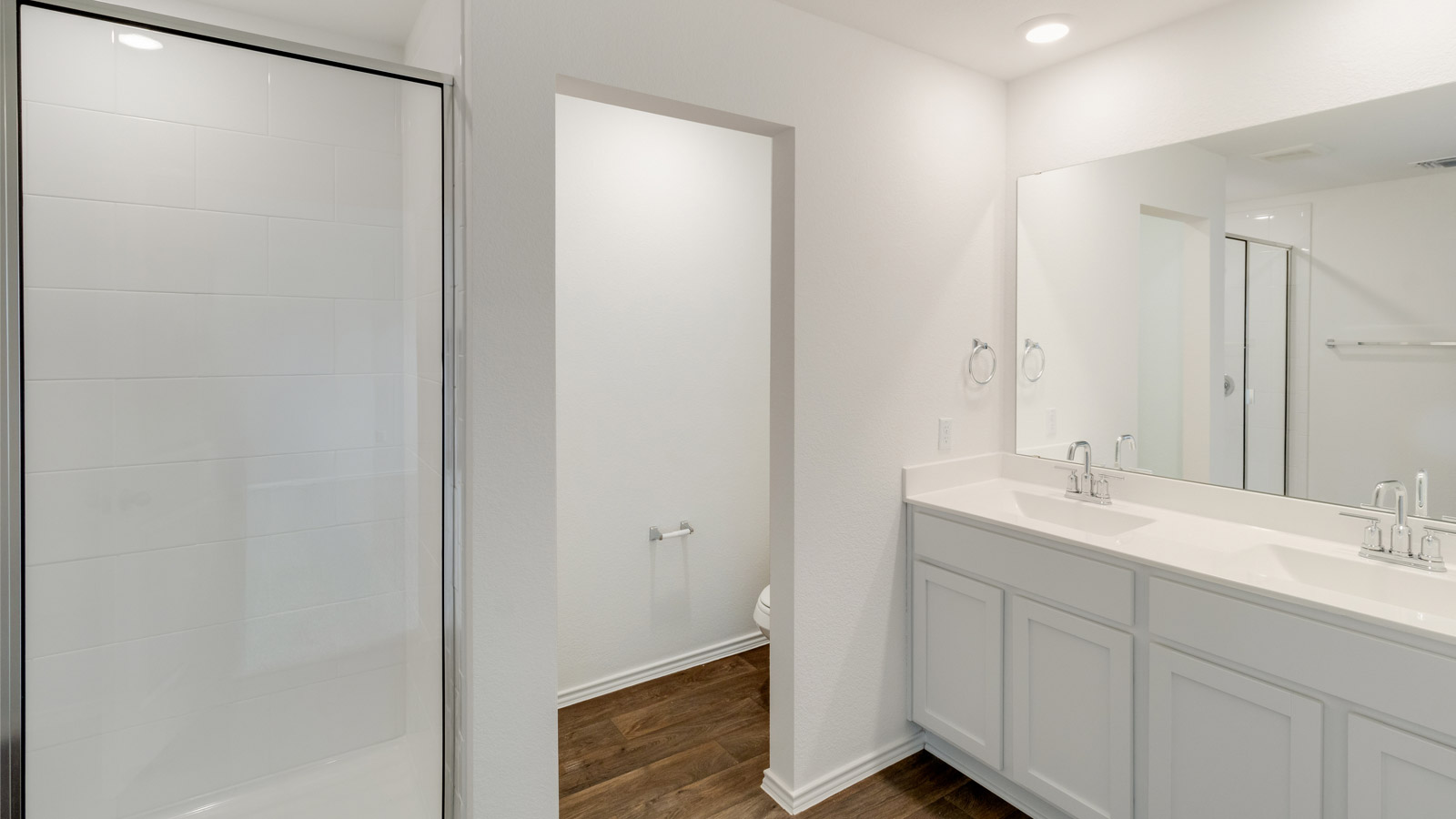 bathroom with dual vanity sinks, toilet,  and a walk in shower