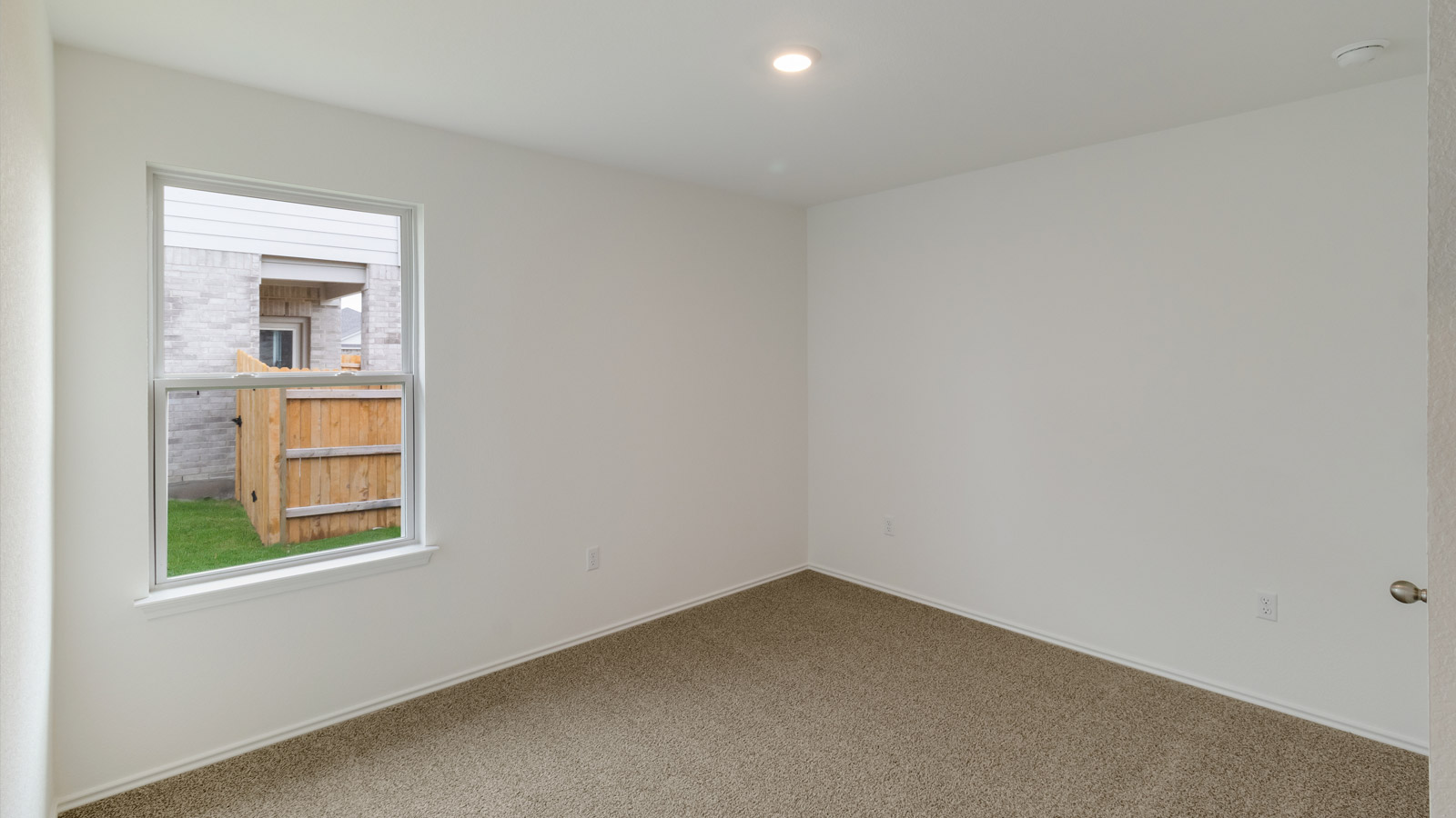 bedroom with beige carpet, white walls and a window