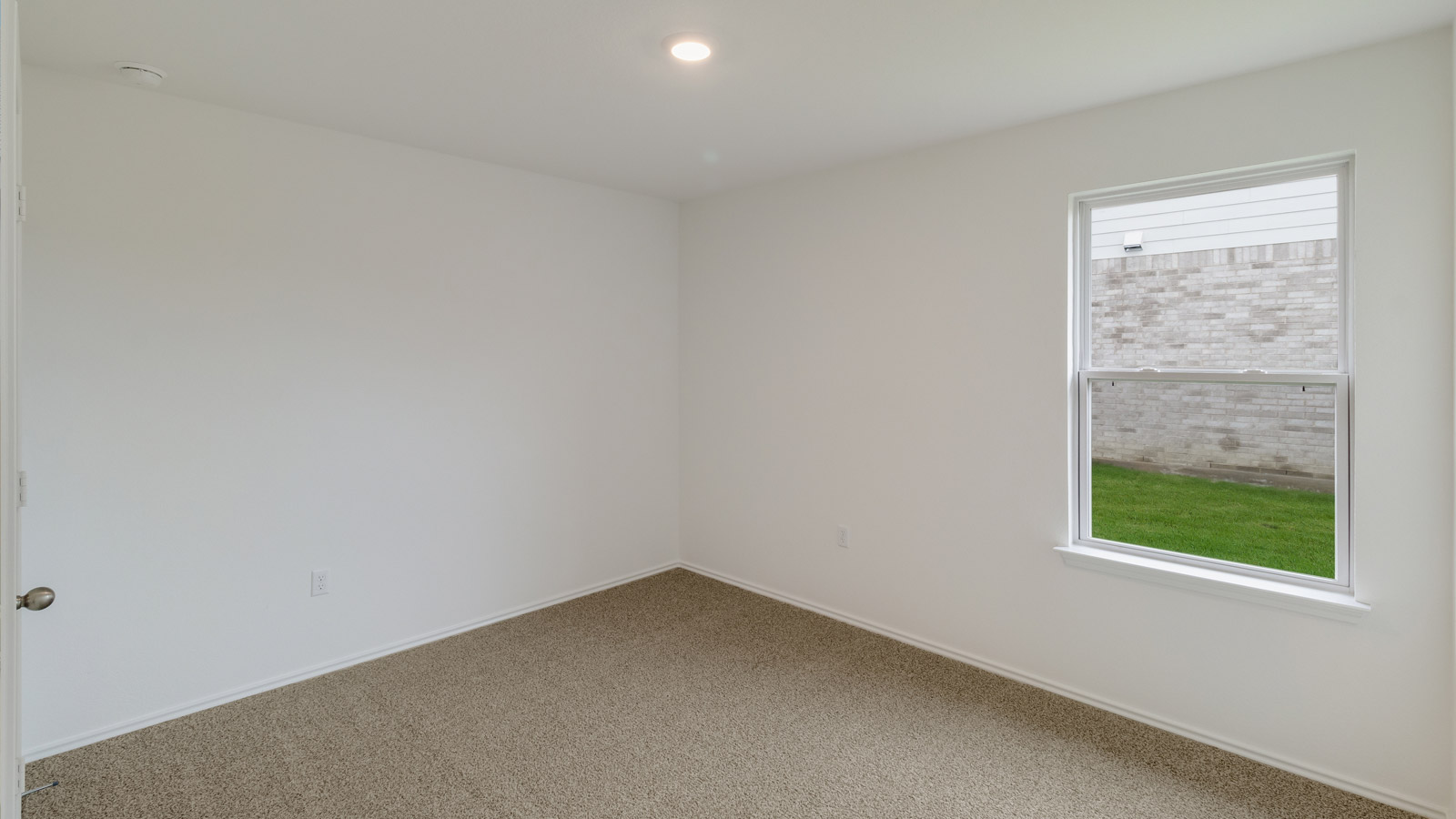 bedroom with beige carpet, white walls and a window