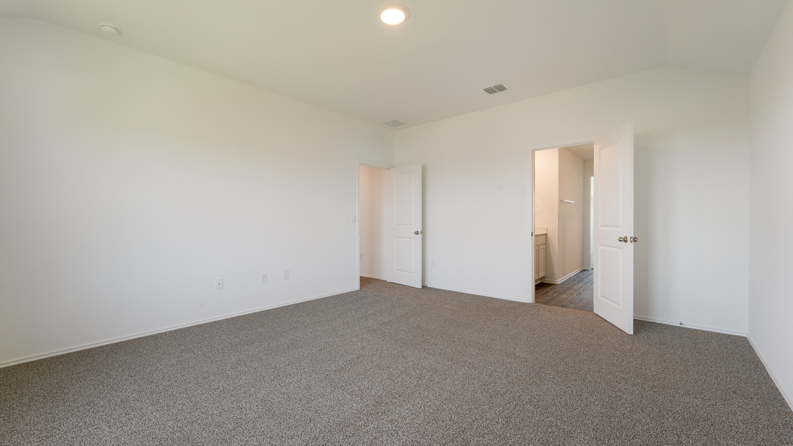 Spacious  main bedroom with carpeted floors. .