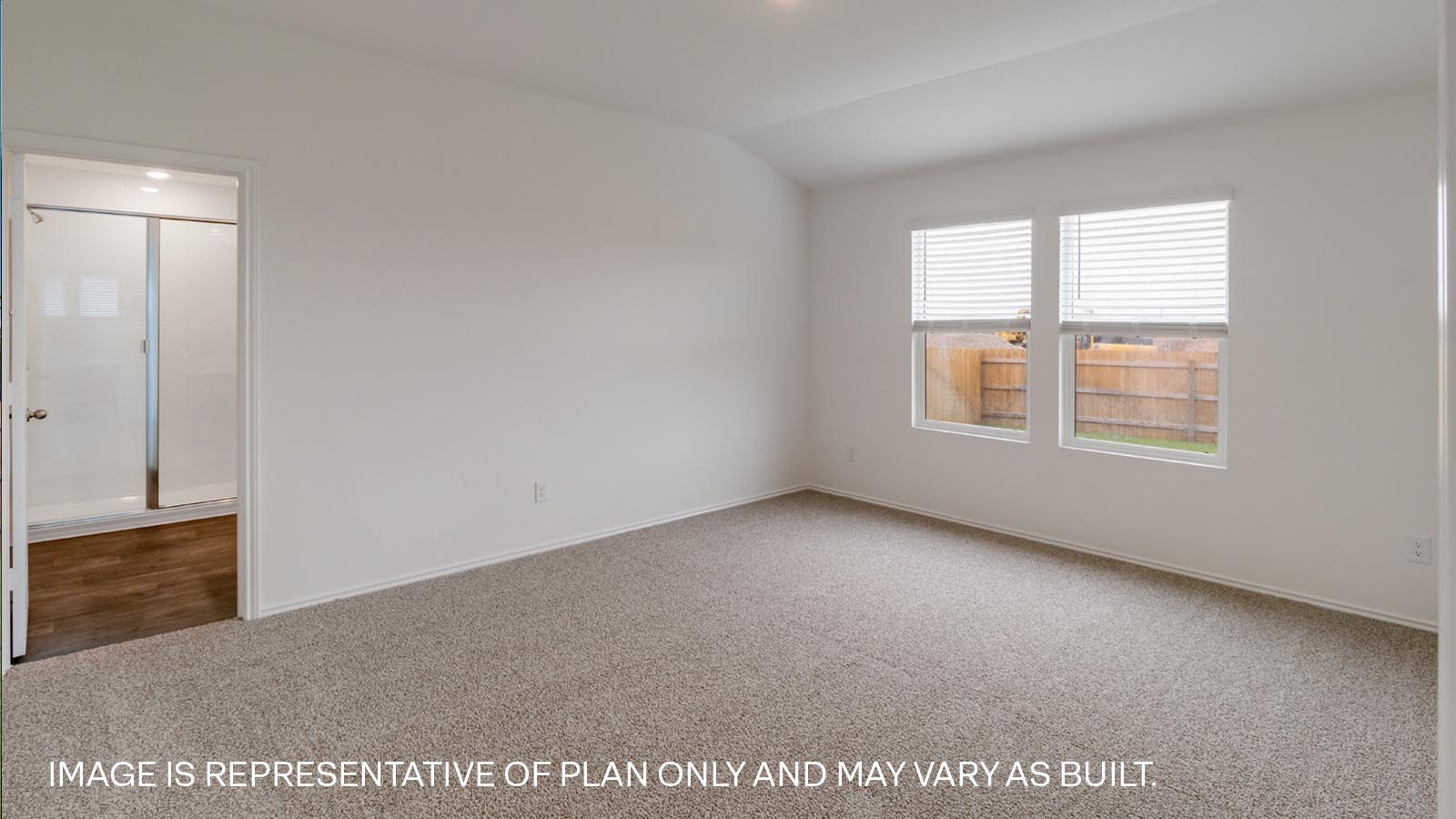Primary bedroom with carpeted flooring and window.