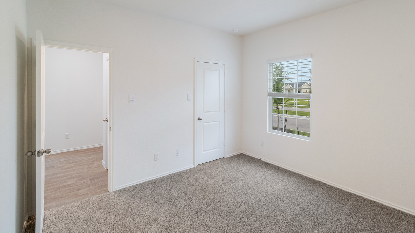 Main bedroom with carpeted flooring and window.