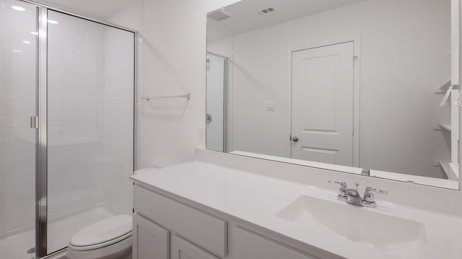 bathroom with dual vanity sinks, toilet, and a walk in shower