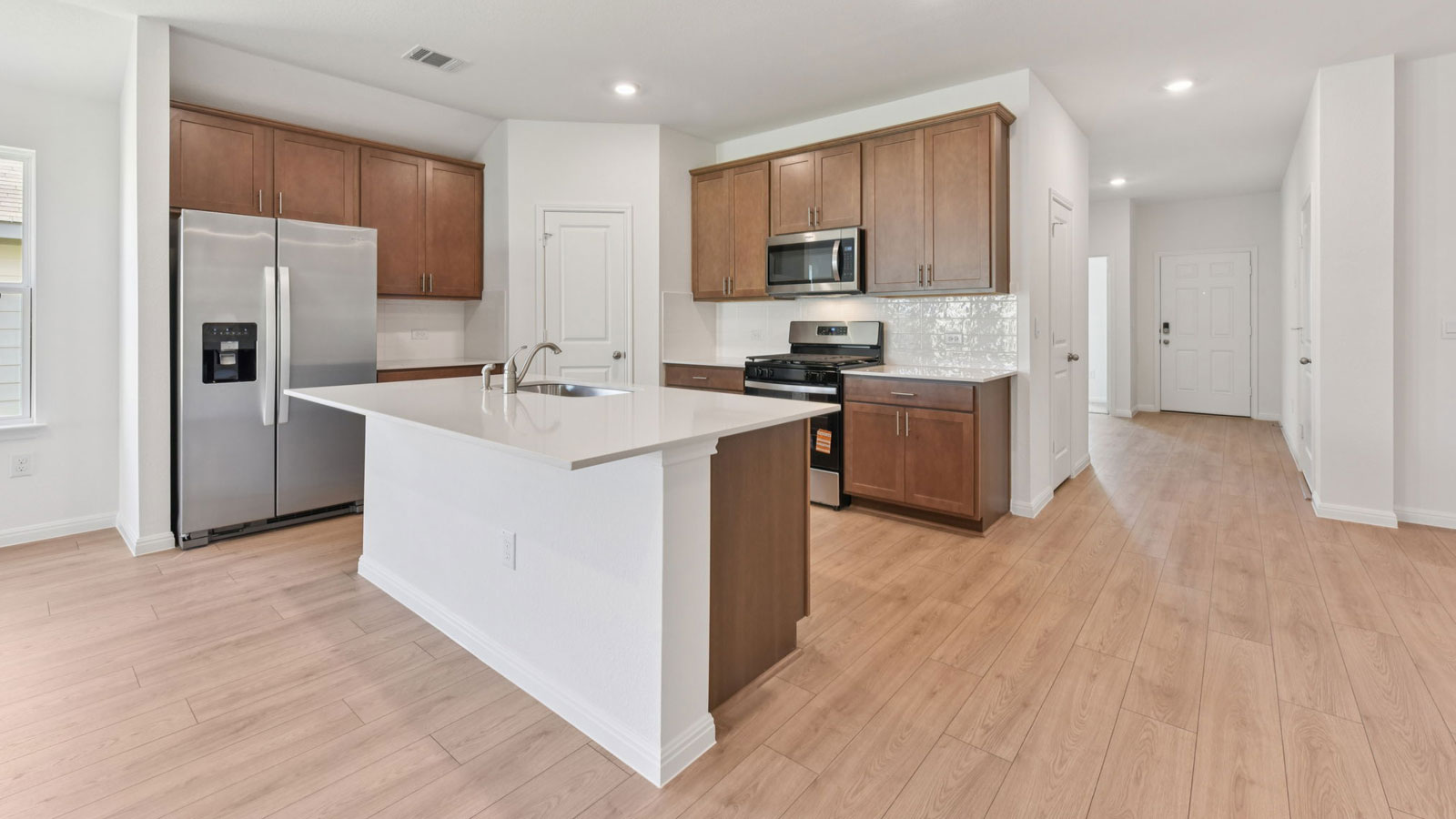 Modern kitchen with quartz countertops, tile backsplash, and 42 inch upper kitchen cabinets.
