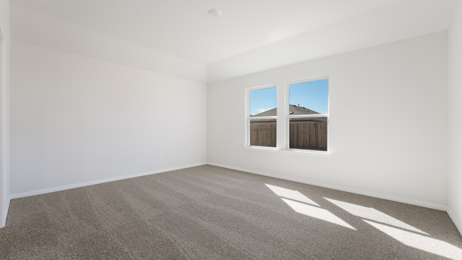 Bedroom 1 with carpeted flooring and large window.