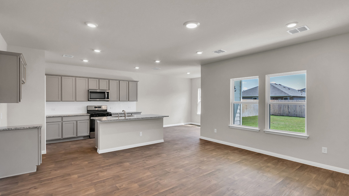 Living room looking to kitchen and dining areas in this new home features natural light, with fresh open concept flow