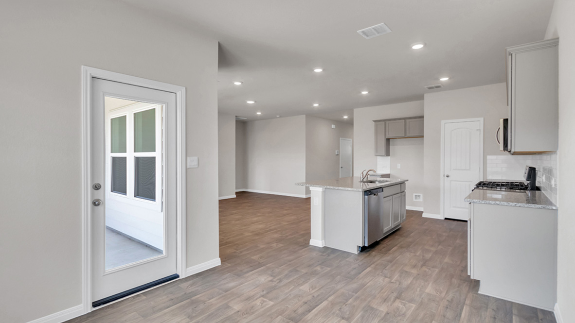 Dining area looking toward modern kitchen island with sink, seating, near backyard, new appliance suite included, Carillon