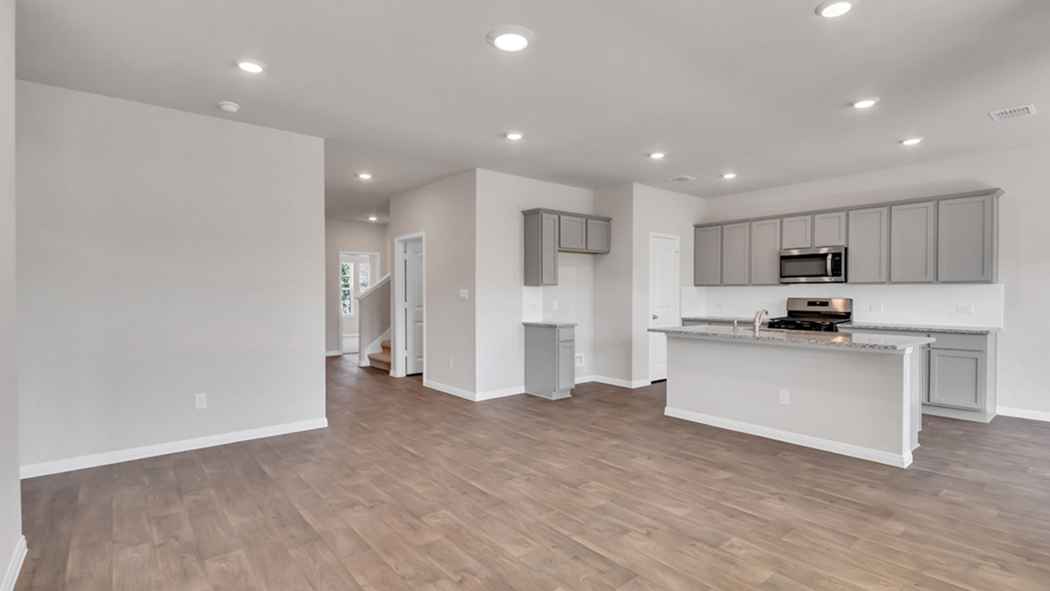 Spacious living room looking toward stairs, modern kitchen island, dining, new appliance suite at Carillon