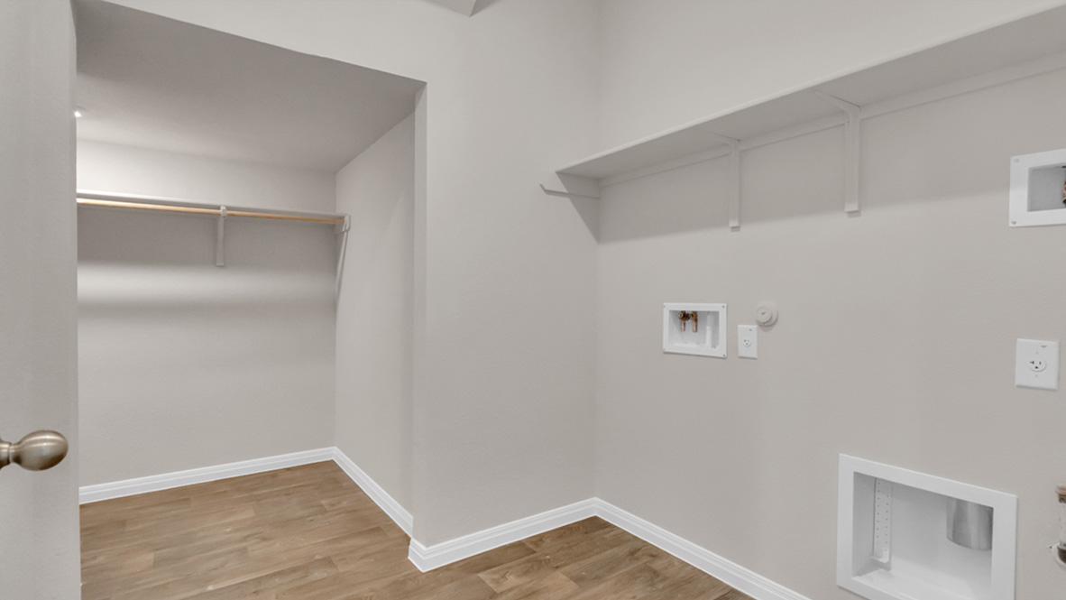 Laundry utility room in Carillon 's new home by D.R. Horton features new washer, dryer included, and overhead storage options
