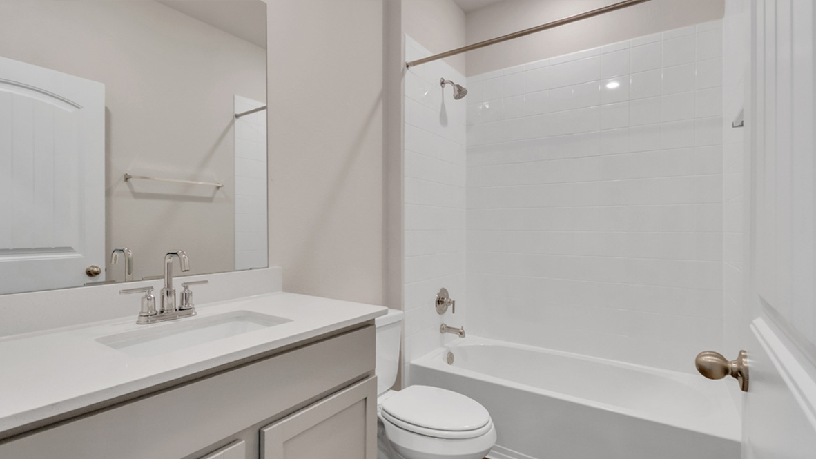 Family bathroom with stylish vanity, mirror, polished fixtures, cabinets, tub-shower combo in Carillon