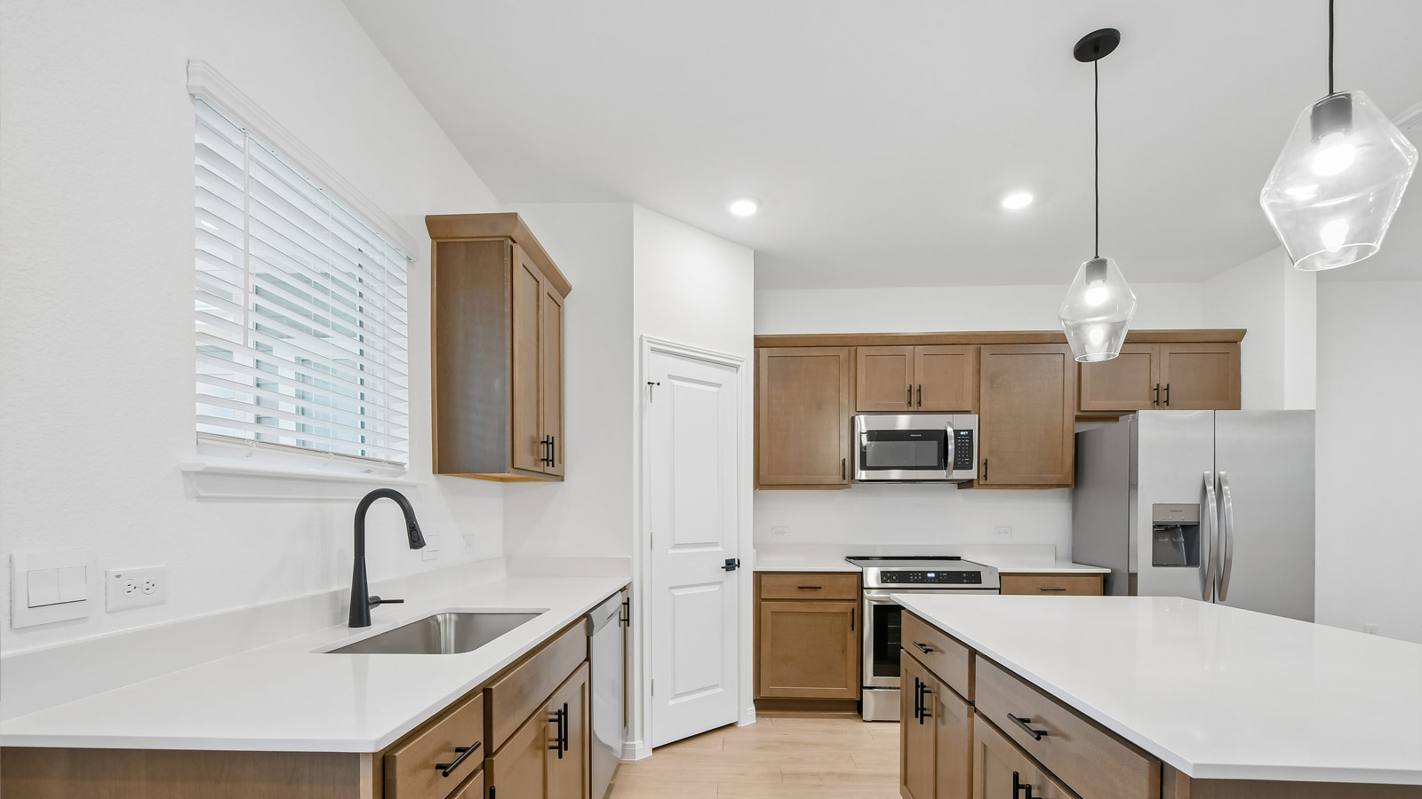 Kitchen with quartz countertops, pendant lights, and picture frame cabinets.