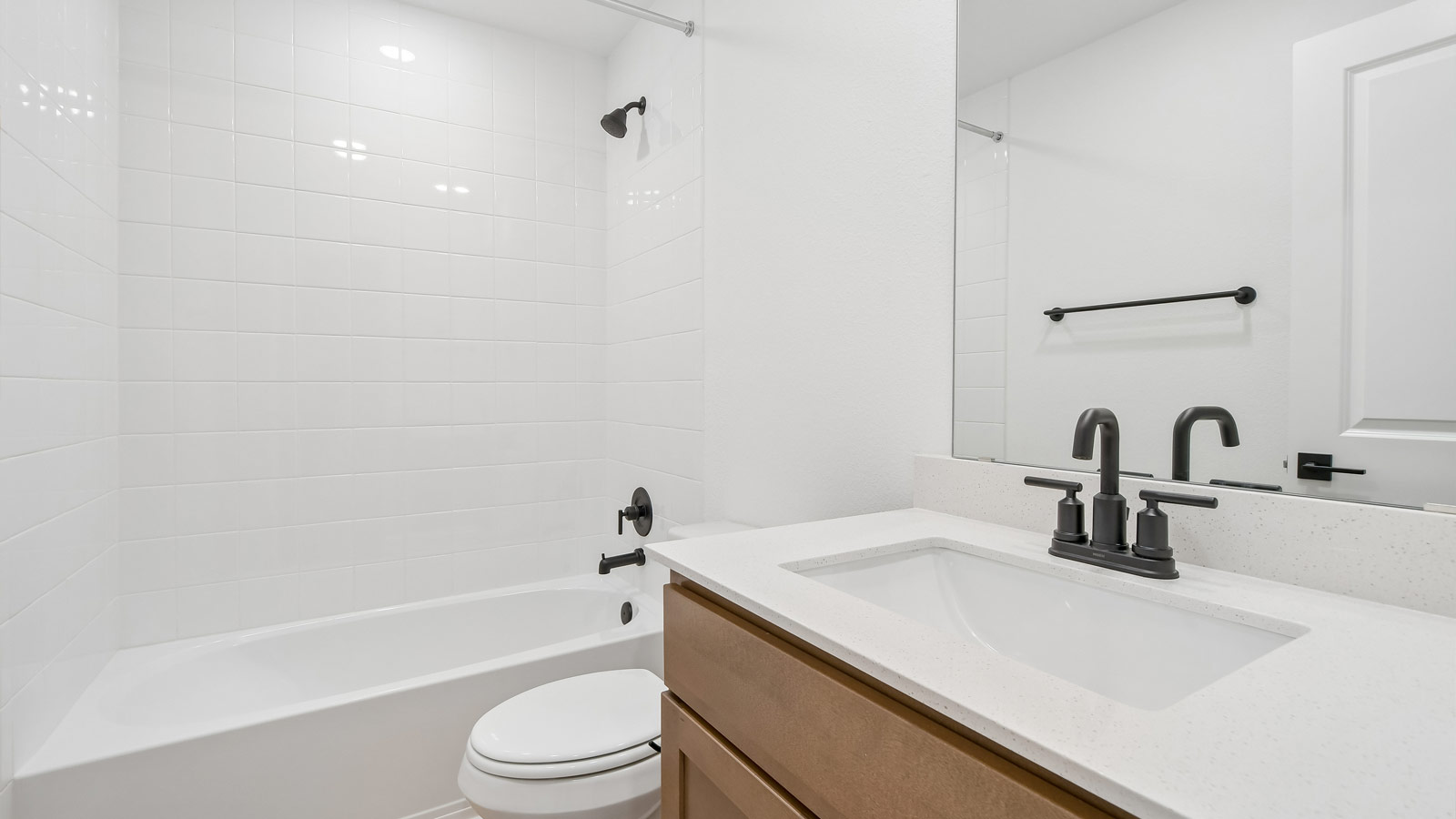 Secondary bathroom with quartz vanity sink, bathtub, and raised shower head.