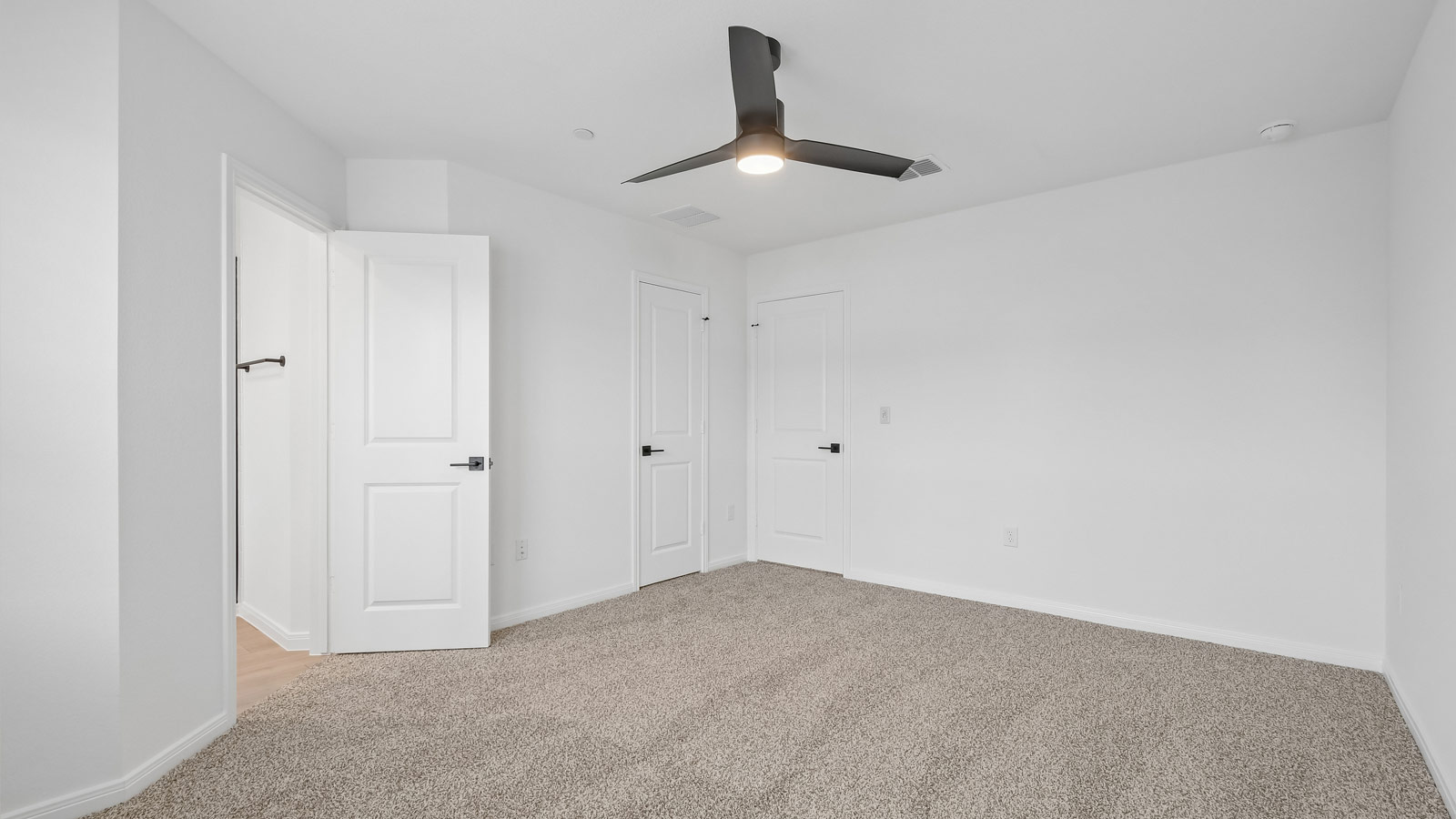 Primary bedroom with carpeted flooring, ceiling fan, and windows.