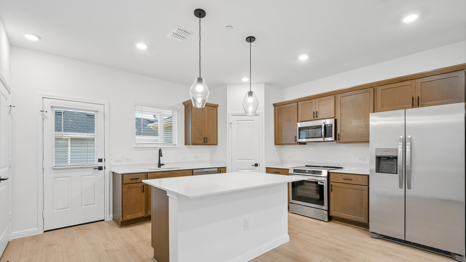 Kitchen with picture frame cabinets, quartz countertops, and black hardware.
