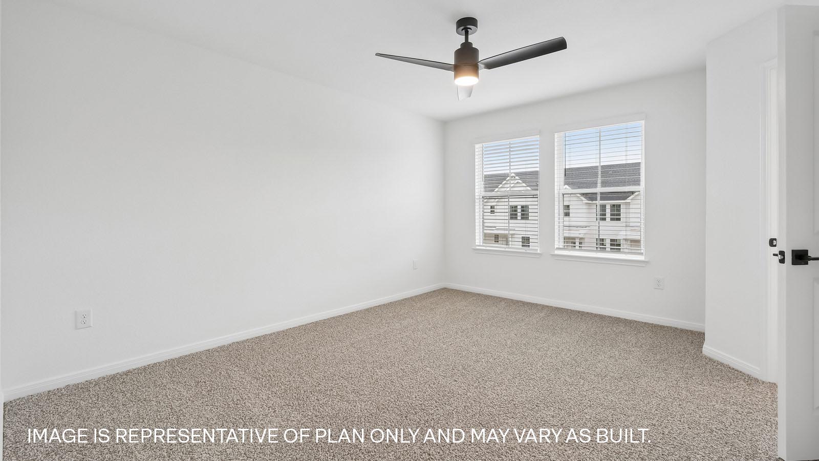 Primary bedroom with carpeted flooring, ceiling fan, and windows.