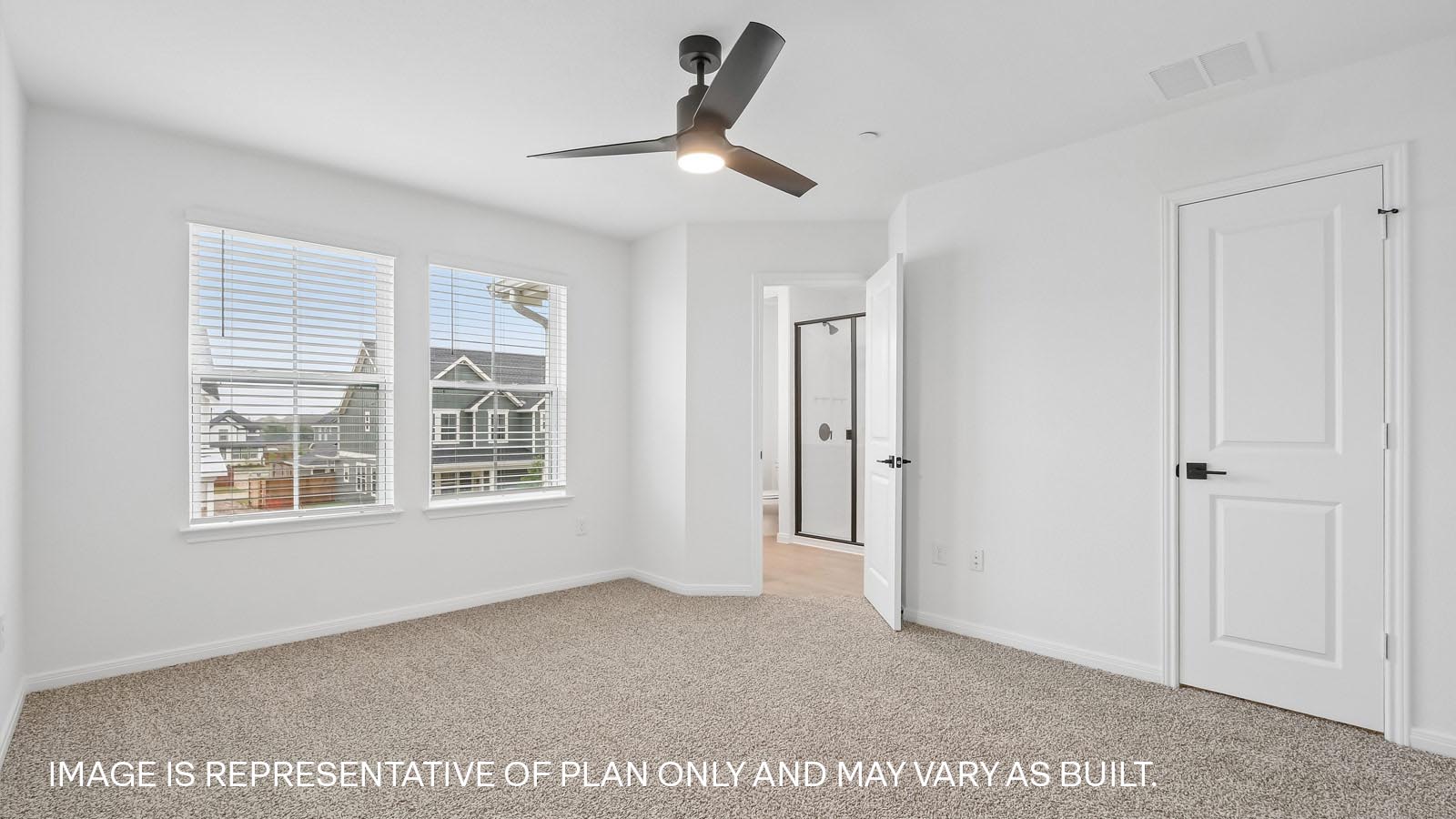 Primary bedroom with carpeted flooring, ceiling fan, and windows.