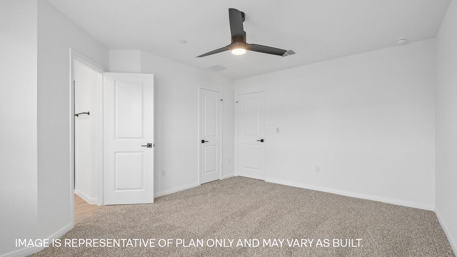 Primary bedroom with carpeted flooring, ceiling fan, and windows.