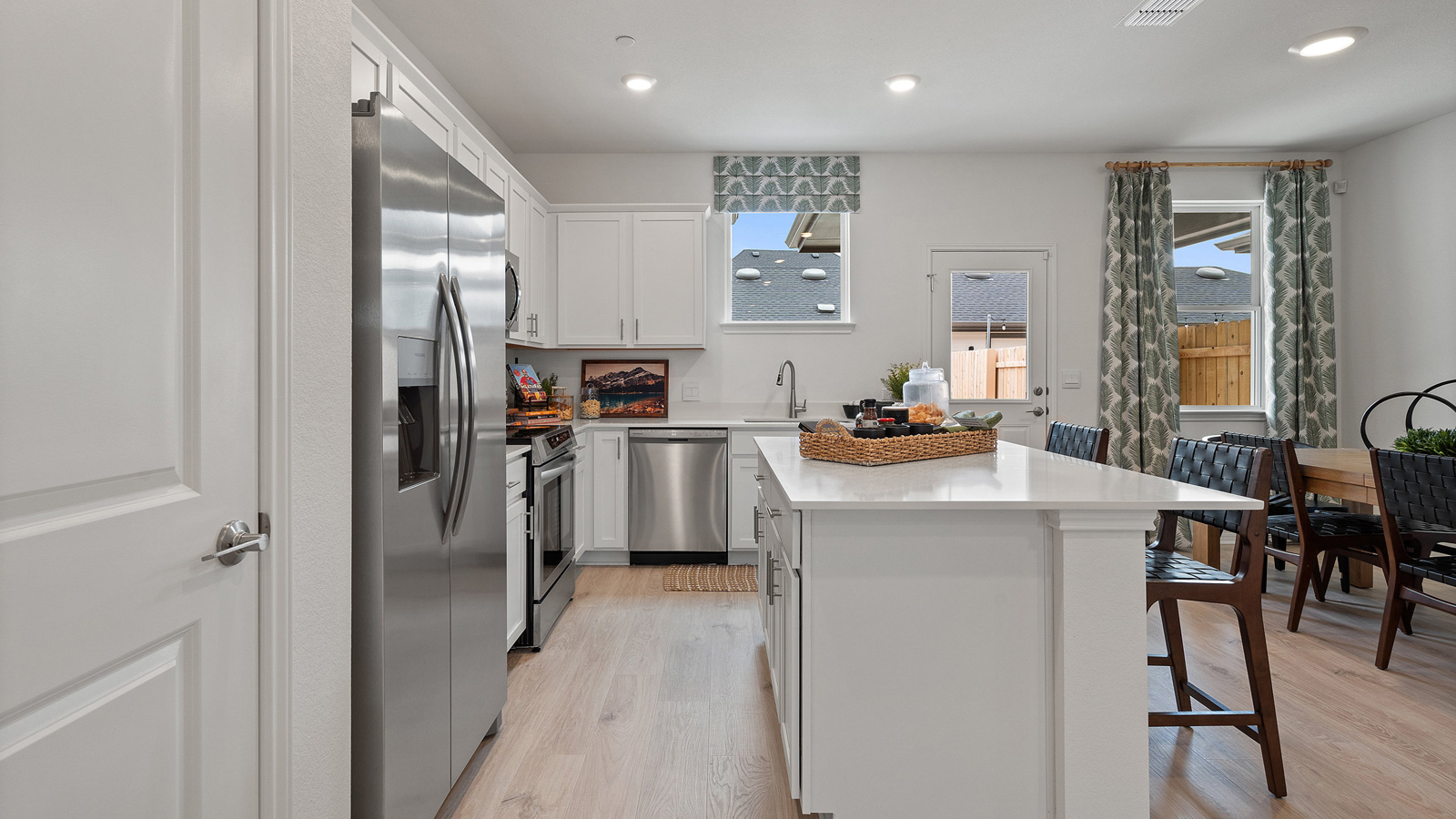Side view of kitchen with pantry, cabinets near dining and living areas near backyard