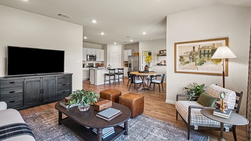 Main living area with clean flooring and natural light connecting to dining area.