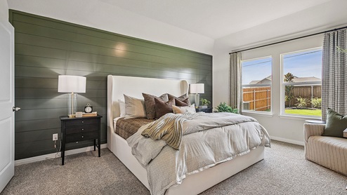 Primary bedroom with carpet, large windows, and simple furnishings.